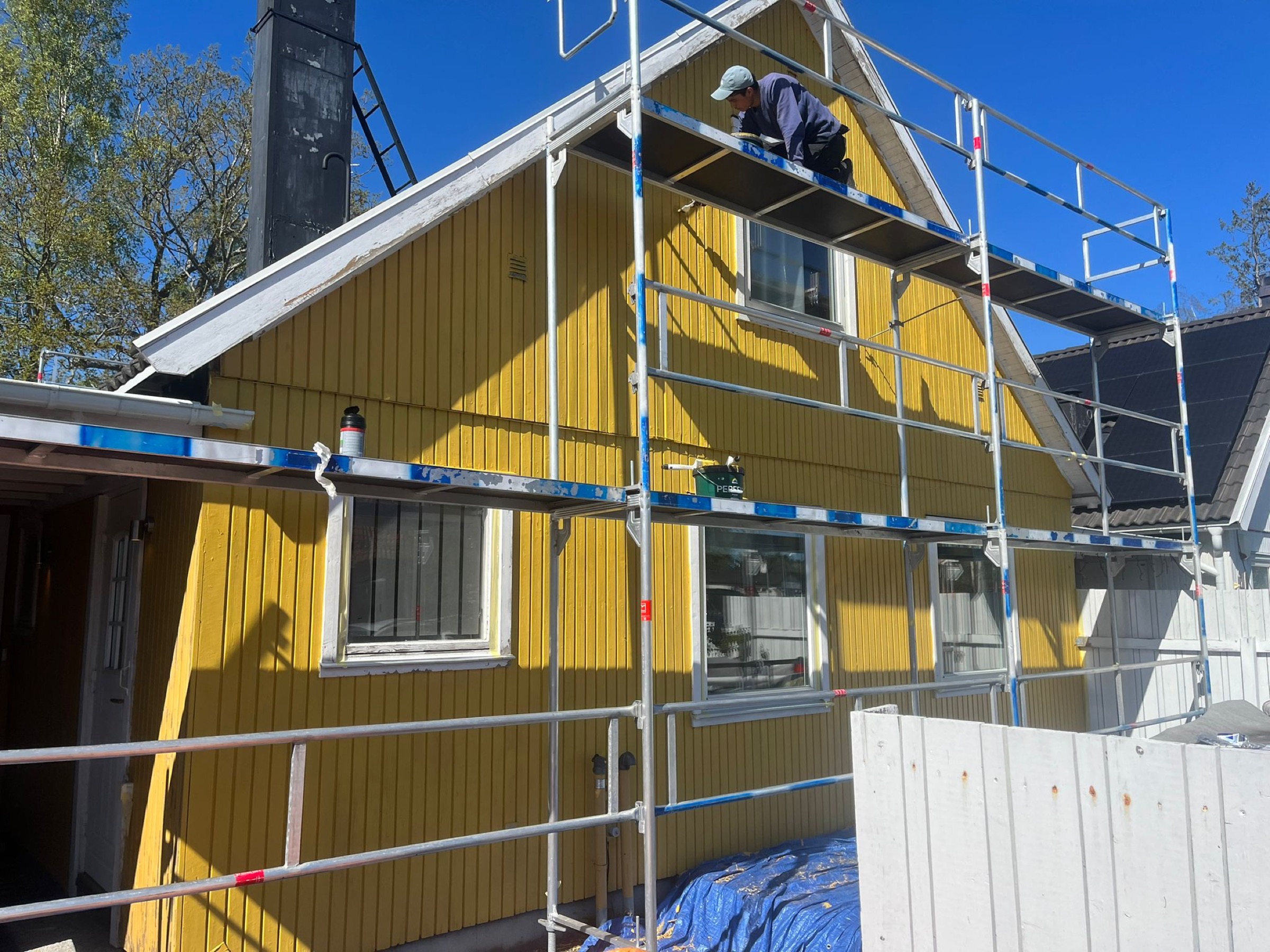 Certifierad montör arbetar på byggställning vid fasadmålning